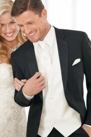 Two models pose for a photo, they appear to be a couple and the man is wearing a black Modern Essential tuxedo with white accessories.