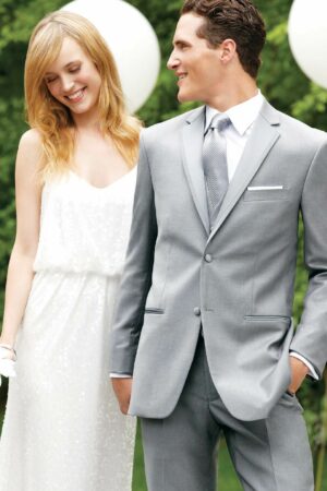A couple poses for a photo, the man is wearing a grey Madison tuxedo.
