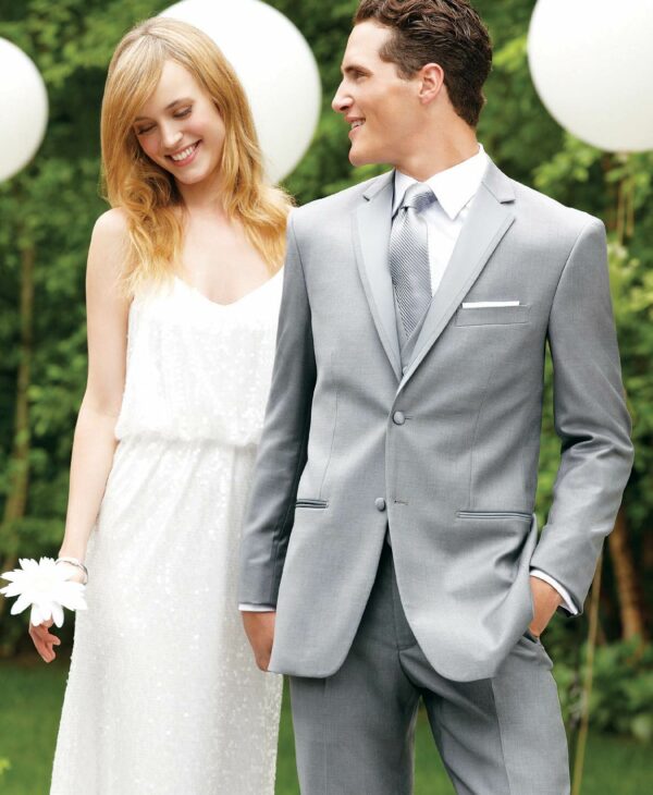 A couple poses for a photo, the man is wearing a grey Madison tuxedo.