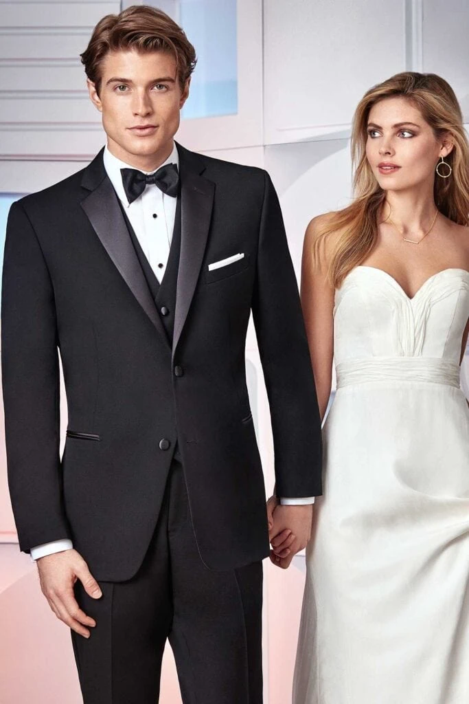 A black tuxedo worn with a black bow tie, shown on a model