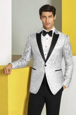 A man poses before a unique backdrop while wearing the White Paisley Tuxedo with black pants.